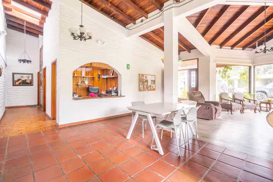 Área social interior con recepción y cubierta alta de madera
